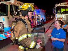In this photo provided by the Fort Worth Fire Department, Fort Worth firefighter Craig Tipton reunites Jamie Wilson with the family's pet frog following a rescue from a house fire in her parents’ in Westworth Village, Texas home, Tuesday night, Sept. 23, 2014. Wilson's parents were not at home at the time of the fire. (AP Photo/Fort Worth Fire Department, Glen E. Ellman)