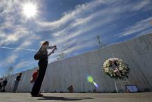 In this Sept. 11, 2012 photo, visitors to the Flight 93 National Memorial pause at The Wall of Names, containing the names of the 40 passengers and crew who died in the crash of United Flight 93, following a memorial service in Shanksville, Pa.