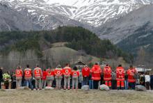 French Red Cross members and inhabitants pay tribute to the victims in front of a stele, a stone slab erected as a monument, set up in the area where a Germanwings aircraft crashed in the French Alps, in Le Vernet, France, Saturday, March 28, 2015. (AP Photo/Claude Paris)