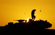 A U.S. soldier walks atop his armored vehicle at sunset as he prepares for a nighttime military exercise in the Kuwaiti desert south of the Iraqi border on Sunday, Dec. 22, 2002. Combat appears to have little or no influence on suicide rates among U.S. troops and veterans, according to a military study that challenges the conventional thinking about war’s effects on the psyche published Tuesday, Aug. 6, 2013 in the Journal of the American Medical Association. (AP Photo/Anja Niedringhaus)