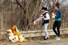 Dominique Ellison, left, and Rickie Bowling, of Warren, bring stuffed animals to a memorial in honor of their friends who died in a car crash on Park Ave. in Warren, Ohio on Sunday. (AP Photo/Scott R. Galvin)