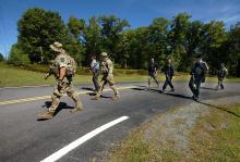 Members of the Pennsylvania State Police and law enforcement conservation officers with the Pennsylvania Game Commission walk from the state police barracks to a wooded area across the street on Route 402 to investigate near where two Pennsulvania State troopers were ambushed Friday, on Sunday, Sept. 14, 2014, in Blooming Grove Township, Pa. (AP Photo/The Scranton Times-Tribune, Butch Comegys)