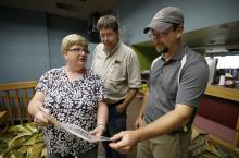 Board members Kay Ross, from left, Jeff Pingle and Jake Pulis look at old photos of the Webster Theater in the lobby, Thursday, Aug. 21, 2014, in Webster City, Iowa. (AP Photo/Charlie Neibergall)