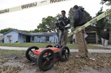 Engineers work in front of a home where sinkhole opened up underneath a bedroom and swallowed a man Friday, March 1, 2013, in Seffner, Fla. Jeff Bush screamed for help and disappeared as a large sinkhole opened under the bedroom of his house, his brother said Friday.