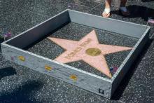 This Tuesday, July 19, 2016 photo provided by Nick Stern shows a six-inch high, concrete-appearing 'wall,' created by an artist known as Plastic Jesus, surrounding the Hollywood Walk of Fame star of Donald Trump in Los Angeles. It appeared the day the former reality TV star and entrepreneur secured the Republican nomination for president. Tourists snapped photos of the wall, topped with razor wire and plastered with "keep out" signs. The tiny wall was gone by Wednesday morning. (Nick Stern via AP)