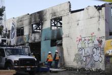 Emergency crew workers walk in front of the site of a warehouse fire in Oakland, Calif., Tuesday, Dec. 6, 2016. The fire erupted Friday, Dec. 2, killing dozens. (AP Photo/Jeff Chiu)