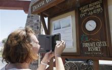 Laura McAlpine, of Scotland takes a picture of the thermometer at the Furnace Creek resort in Death Vally National Park Friday, June 28, 2013 in Furnace Creek, Calif. Excessive heat warnings will continue for much of the Desert Southwest as building high pressure triggers major warming in eastern California, Nevada, and Arizona. (AP Photo/Chris Carlson)