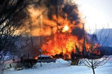 A setting sun shines through the heavy smoke and flames at this home in Greenwood Township Thursday evening. (Press Enterprise/Keith Haupt)