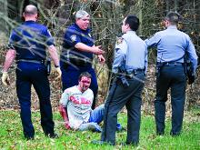 A man identified by a driver's license police obtained on the scene as Darrin Bellum is shown surrounded by police after he ran from a crash on Fowlersville Road that injured a female passenger. Police found Bellum on a cul de sac off Hidlay Church Road bleeding. (M.J. Mahon/Press Enterprise)