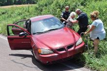 Scott Township Sgt. Joe Grassley, left, and officer Vince Taggart, second from right, assist the driver of a Pontiac from her car to her walker after the vehicle went off the side of Neufer Hill Road in Scott Township on Monday afternoon. (Press Enterprise/Jimmy May)