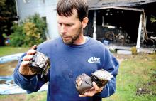 Derek Smith identifies a Whitey Ford autographed baseball he picked out of the remains of his 92 Butler Court home in Shickshinny on Wednesday morning. He, his wife Kim and their 2-year-old son Tristyn escaped the midnight fire unharmed but lost nearly all their possessions. (Press Enterprise/Bill Hughes)