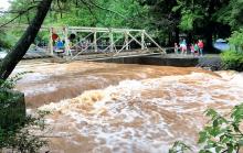 People at Knoebels Amusement Park Resort stop at the bank of Roaring Creek at the park Monday to get a look at rising waters. The park was closed to the public Monday due to the threat of flooding. (Press Enterprise/Keith Haupt)