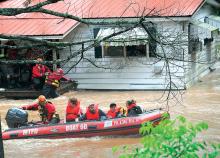 McLaughlin family members are taken from their home along Roaring Creek near Queen City Road in Locust Township Wednesday morning by members of the East End and Reliance Fire Company water rescue crews. (Press Enterprise/Keith Haupt)