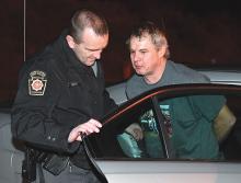 Cpl. Greg Fraley escorts David Albertson out of a State Police cruiser at the Bloomsburg barracks Thursday night after police took him into custody at his Fishing Creek Township home. (Press Enterprise/Jimmy May)