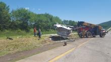 Workers from Falzone Towing clean up dog crates and the remains of a trailer following an early morning wreck Tuesday.