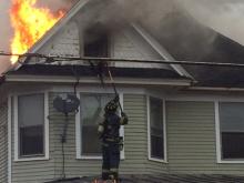 A firefighter works to break a window at 505 E. Second St. on Wednesday morning. (Press Enterprise/Peter Kendron)