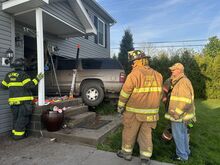 Press Enterprise/Susan Schwartz Firefighters wait for a tow truck after rescuing a driver from an SUV that plowed into a house early Thursday.