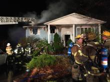 Firefighters wait outside a house on Mingle Inn Road as crews douse hot spots after a fire early Friday. (Press Enterprise/Kristin Baver)