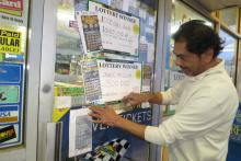 Thakor Patel smooths the tape on the sign announcing his store, Berwick Sunoco, sold a $300,000 winning instant lottery ticket Tuesday. (Press Enterprise/Susan Schwartz)