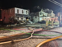 Firefighters confer in front of 537 and 533 Broad St., two houses heavily damaged by fire early in the morning of New Year's Day. (Press Enterprise/Drew Mumich)