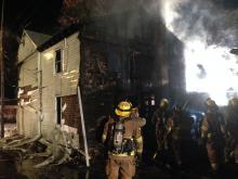 Firefighters work to quench flames at the rear of 311 DL&W Ave. late Tuesday night. (Chris Krepich/Press Enterprise)