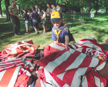 Wolf scout Hunter O’Neal picks up a pile of American flag before getting in line at the fire to properly destroy them during a June ceremony at Town Park in Bloomsburg by Troop and Pack 24.
