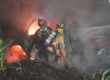 Firefighters knock down the flames which were consuming a pickup which was about 30 to 40 feet down the embankment off of Mainville Drive Monday night. (Press Enterprise/Jimmy May)