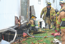 Firefighters work to douse hotspots under a trailer at 6 Rhodes St. in Almedia.