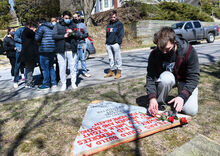 Christopher Herman, right, places a rose and a candle at the site of a 2000 fire that killed three members of the TKE fraternity on Fourth Street in Bloomsburg. Press Enterprise/Keith Haupt