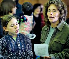 Anna Weber-Loomis, 11, and her mom Leticia Weber, Bloomsburg, sing along with others the Woody Guthrie song “This Land is Your Land” at the Martin Luther King, Jr. Community Program and Dinner at the Moose Exchange in Bloomsburg on Sunday afternoon. 