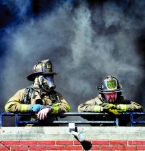 Two firemen rest on the third-floor balcony as smoke pours out of the third floor of the Moose Exchange in Bloomsburg on Thursday.