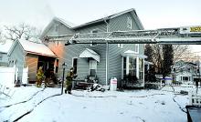 Firefighters work to fight a fire in a wall of a home Saturday morning on Second Street in Espy. 