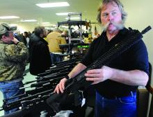 Dealer and gunsmith Jami Nolan of Montoursville holds a AR-15 semi-automatic military-style rifle while talking about its weight and other features while standing at his table at the Benton Fire Company's Gun Show Saturday afternoon. 