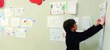 Henry Podeschi, 13, helps hang drawings which kids have submitted for the new design of Kidsburg