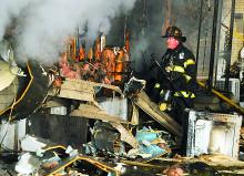 Berwick firefighter Steve Powers works to tear apart a burned trailer.