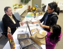 Local author Pastor Robert Andrews hands an autographed copy of his book Dangerous Curves to Jamaica Ash, 11 who along with her sister Gabriela Ash, 6, lower right, stopped by at the Thomas Beaver Free Library on Thursday to pick up the book during the signing. (Press Enterprise/Jimmy May)