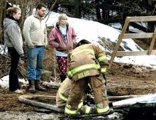 Michelle Brown, standing in background third from left, 42, and two family members watch firefighters extinguish a fire that destroyed the family’s horse barn in South Centre Township on Thursday morning. 