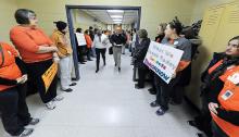 Danville School Board members Dawn Koons-Gill and Randy Keister walk through a hallway lined by picketing Danville teachers and their supporters on the way to the cafeteria for Tuesday evening board meeting at the high school in Danville. The teachers union and school board have not come to a contract agreement after nearly three years of talks.