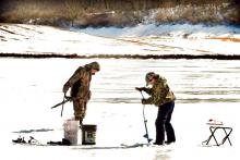 Jonathan Klingerman, left, 13, of Berwick, moves his stool as his brother Matthew Klingerman, 10, drills a new hole on Briar Creek Lake on Sunday afternoon. It’s catch and release time in March but the boys said they hadn’t caught any to release. Although the weather has been balmy over the weekend, they said the ice still measures 14 inches thick. 