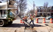 Sokol workers Casey Stine, left, and John Sokol shovel concrete from a Dan-Ber truck into a large pothole at the intersection of Fourth and Market streets in Bloomsburg on Tuesday. The hole is on top of a recent excavation for the new United Water water line that runs under Fourth Street. 