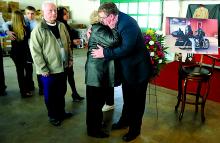 Mark Williams, right, brother of Kirk Williams, is hugged by his aunt Carol Stout as mourners line up to pay respects to Kirk Williams Saturday at his Eyers Grove auction house. The family held the funeral, attended by hundreds, at Williams' business.