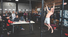 Friends and family cheer on Adam Bowman (right) as he goes for the 4,801st and final pull-up to set the new Guinness Book Record for pull-ups in an 8 hour span Saturday afternoon at Cross Fit Bloomsburg in Bloomsburg.
