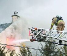 A firefighter climbs a ladder truck to fight flames from above during a house fire on Sunday evening at 7175 Colombia Boulevard, Bloomsburg.