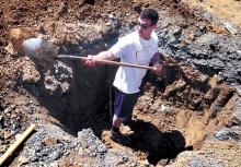 Robbie Loglisci, a Bloomsburg University junior from Yardley, digs a hole at the Kidsburg site during a pre-build work day on Sunday. Relocated on higher ground, using sustainable materials, the new Kidsburg replaces the old Kidsburg destroyed during the 2011 flood. 