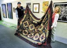 Moose Exchange Executive Director Oren Helbok and quilt maker Rita Millard display the quilt called “Tonga Rhapsody” that Millard and Barbara Persing, who did the piecing, are donating to the Moose Exchange. 