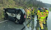Firefighters gather around an SUV resting on its side.