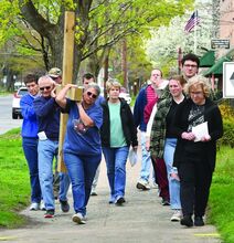 The faithful take turns carrying a cross along Market Street in Bloomsburg Friday while re-enacting Jesus’ final walk. 