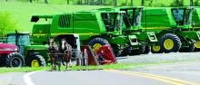 Two women in an Amish buggy pass by a row of combines for sale along Route 44 just south of Jerseytown on Friday afternoon.