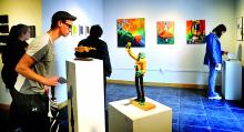 Bloomsburg University sophomore Adam Sosnoski examines three-dimensional works on pedestals during the opening reception for the Senior Exit Show.