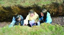 Benton Middle School students Savannah Ross, Kaylee Steinruck and Julee Spade look at the different layers of soil inside the Soils Pit during the Envirothon Wednesday at the Montour Preserve. 